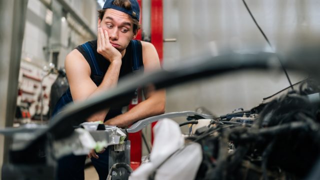 A frustrated mechanic looking at a car engine