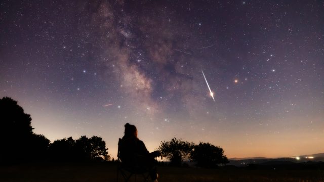 The silhouette of a person looking up at the night sky