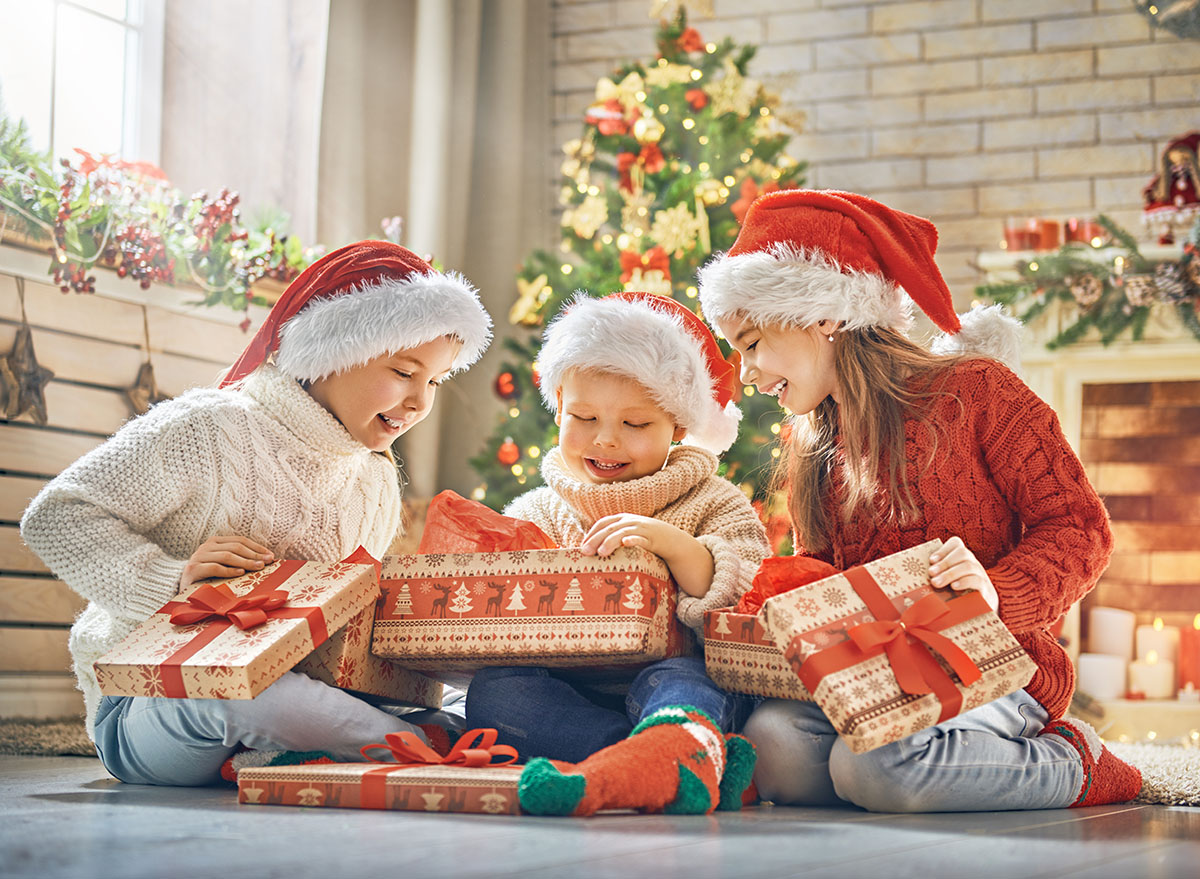 Merry Christmas and Happy Holidays! Cheerful cute children opening gifts. Kids having fun near tree in the morning. Loving family with presents in room.