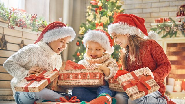 Merry Christmas and Happy Holidays! Cheerful cute children opening gifts. Kids having fun near tree in the morning. Loving family with presents in room.