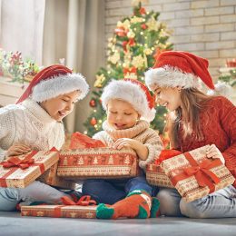 Merry Christmas and Happy Holidays! Cheerful cute children opening gifts. Kids having fun near tree in the morning. Loving family with presents in room.
