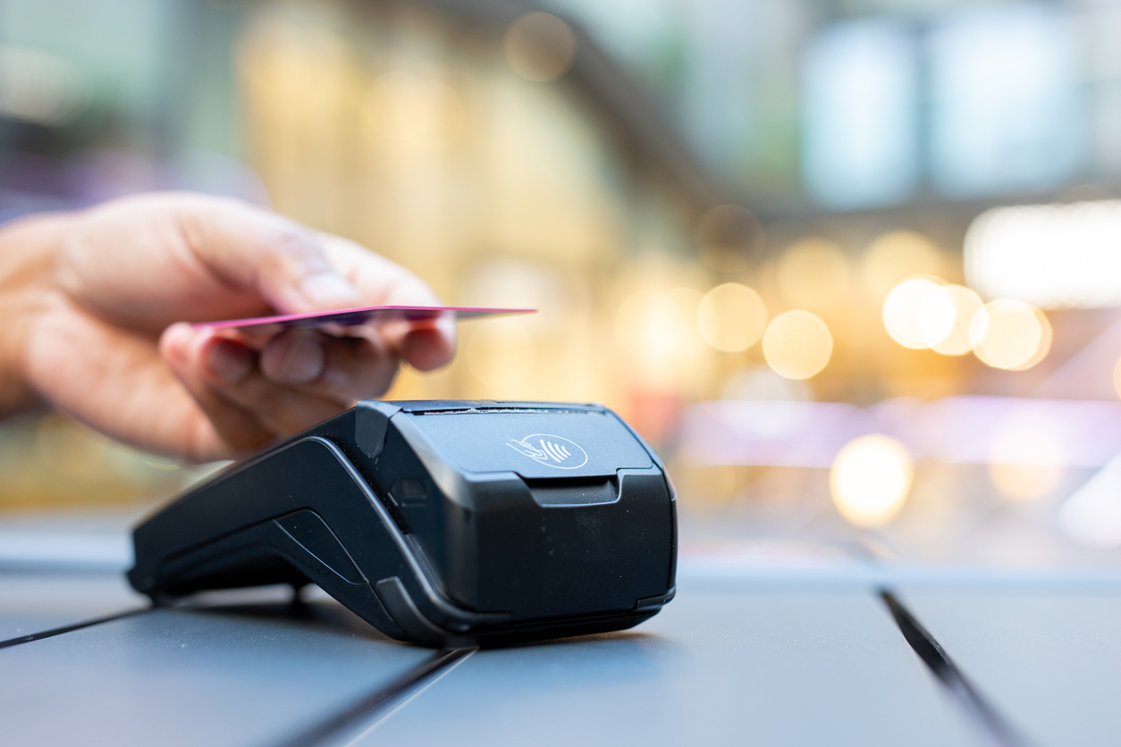 A close up of a person tapping their debit or credit card on a payment terminal