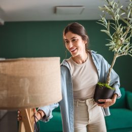 young woman arranging a lamp and a plant in a green room