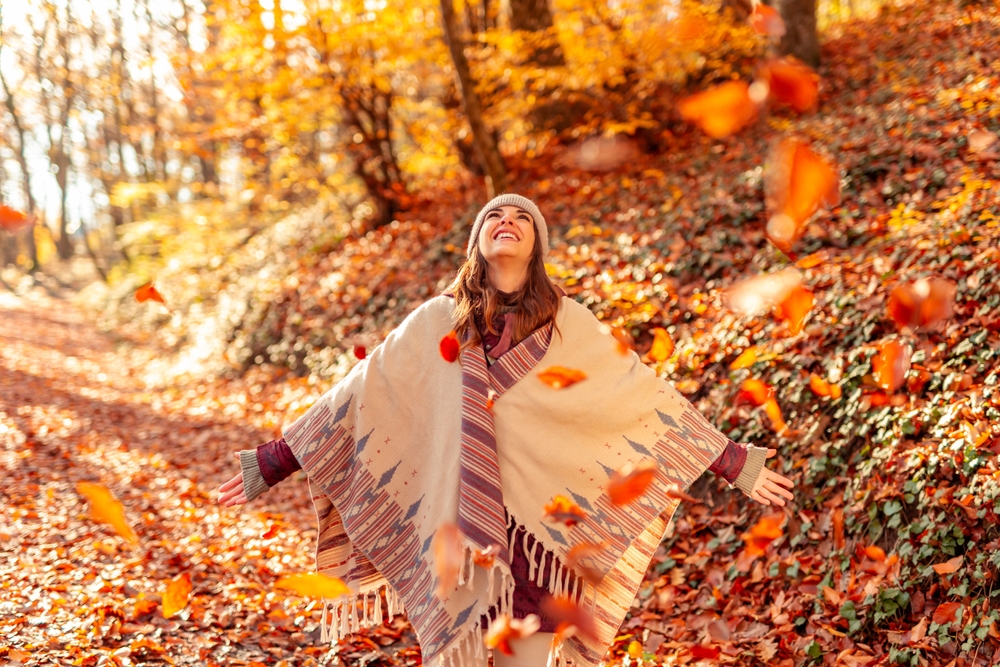 A woman standing in the woods surrounded by fall foliage