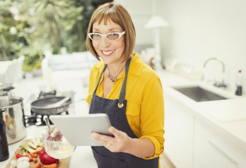 woman with short bangs in the kitchen following a recipe on her ipad