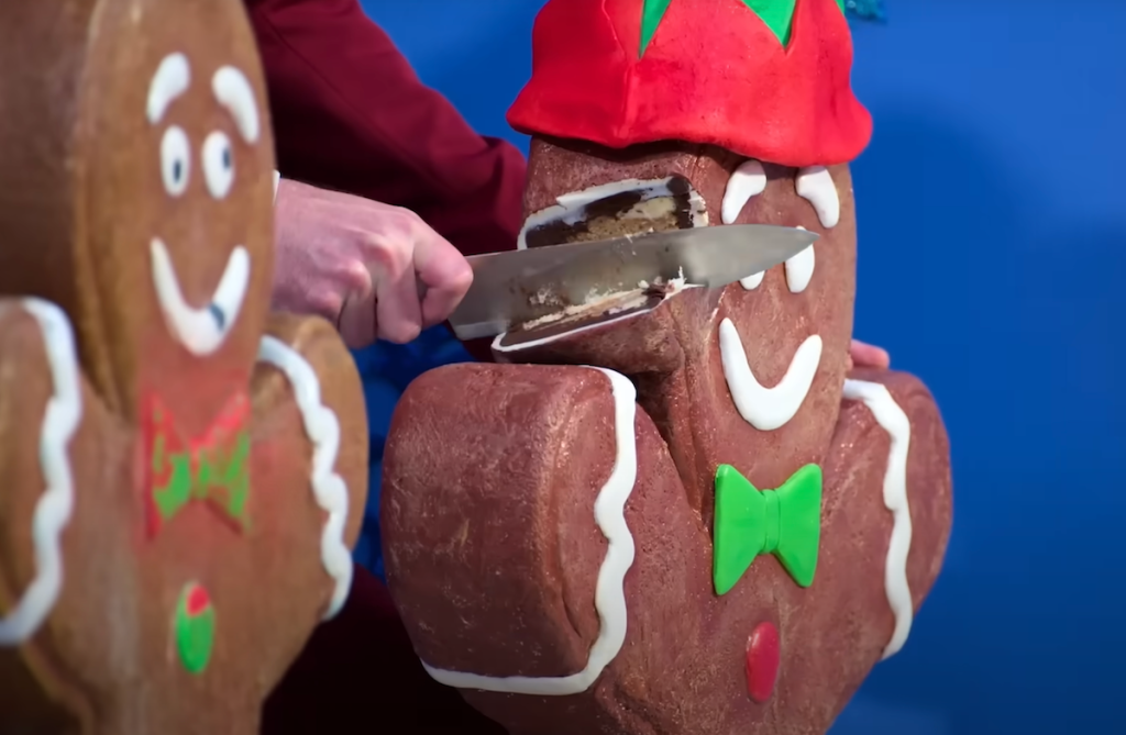 A knife cutting into a gingerbread man cake