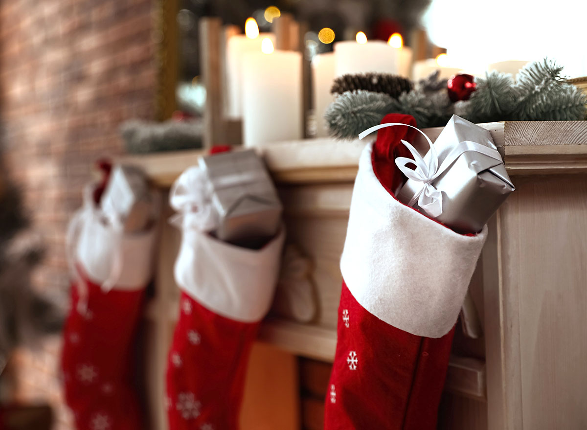 Decorative fireplace with Christmas stocking and gifts in stylish room interior