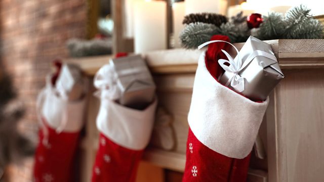 Decorative fireplace with Christmas stocking and gifts in stylish room interior
