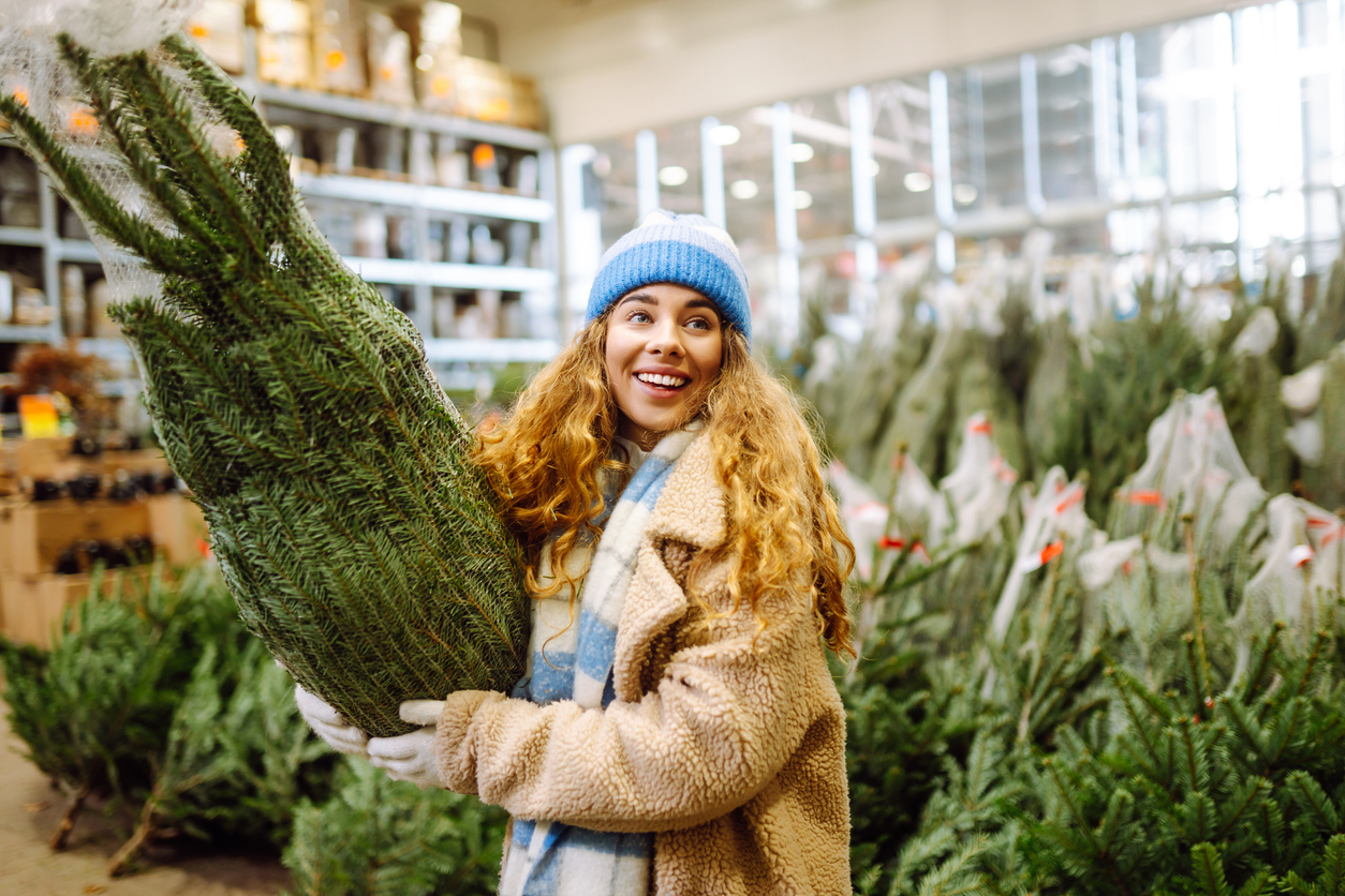 A woman buying a Christmas tree from a lot