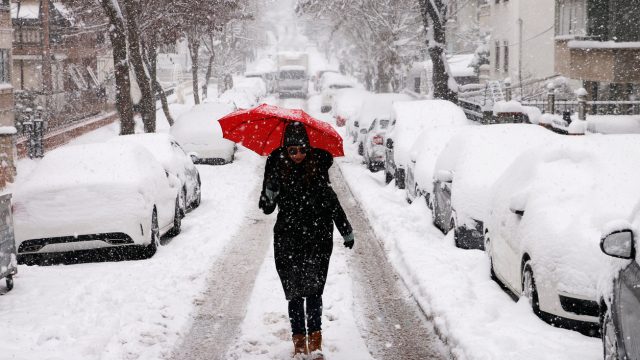 A young woman walking through the snow in a city
