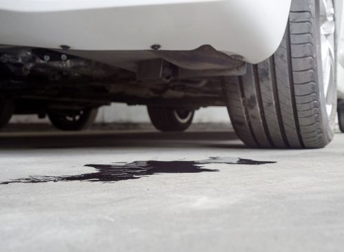 Selective focus of Engine oil stains of car Leaking under the car on blurred Car parked background.