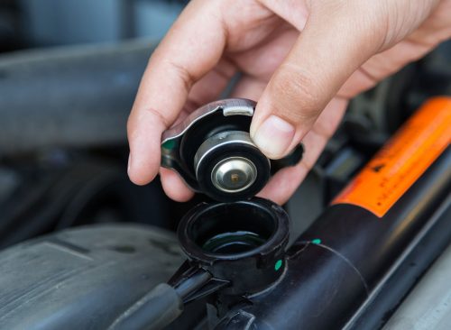 Closeup hand open valve metal cover on an radiator for engine cooling