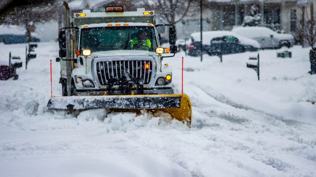 Heavy equipment driver working to push snow to the side of the streets after a blizzard