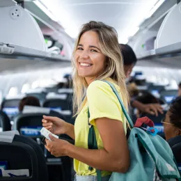 Happy woman boarding the airplane and looking at camera.