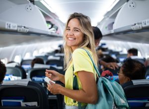 Happy woman boarding the airplane and looking at camera.