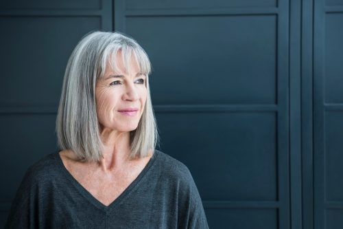 portrait of a woman with a gray bob wearing a charcoal shirt against a dark gray background