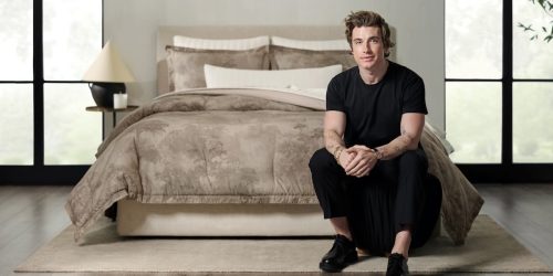 Jeremiah Brent sitting on a bed with his Walk in the Woods comforter