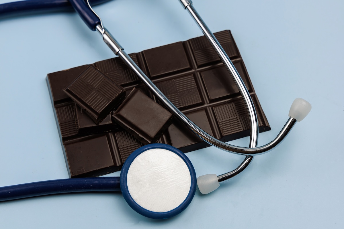 dark chocolate bar and a stethoscope on a light blue background