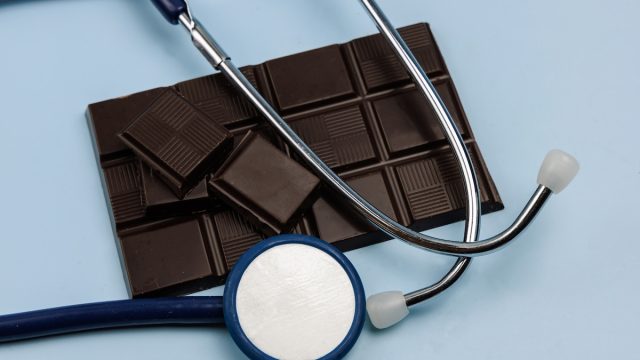 dark chocolate bar and a stethoscope on a light blue background