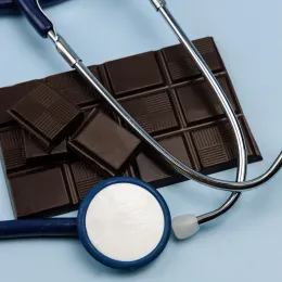 dark chocolate bar and a stethoscope on a light blue background
