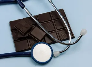 dark chocolate bar and a stethoscope on a light blue background