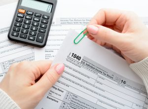 A woman sitting at a table and holds a tax form