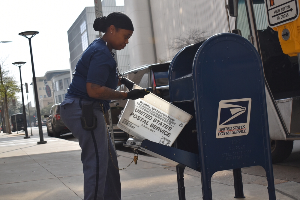 A postal worker emptying a mailbox