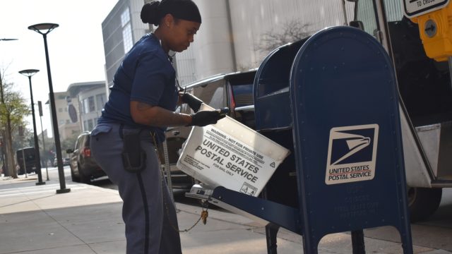 A postal worker emptying a mailbox