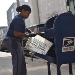 A postal worker emptying a mailbox