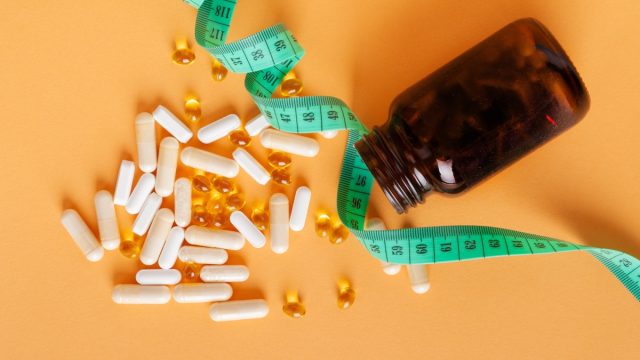 supplements and a measuring tape on an orange background