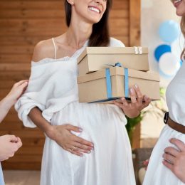 pregnant woman in a white dress accepting gifts at her baby shower