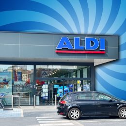 9 Best New Aldi Finds Hitting Shelves in August. Alicante, Spain - May 27, 2025: ALDI store front displays modern design with a parked black vehicle and shopping carts, creating a lively shopping atmosphere