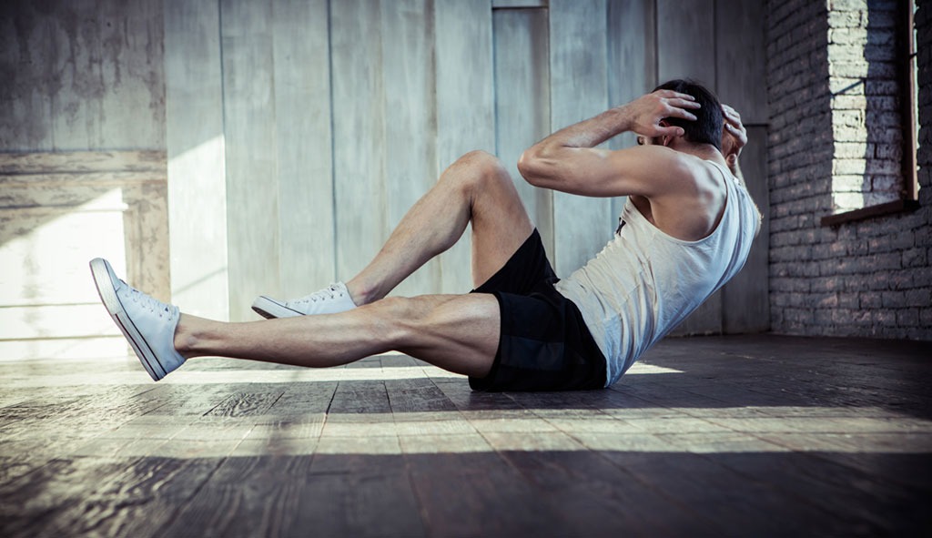 Man doing bicycle crunches on wood floor