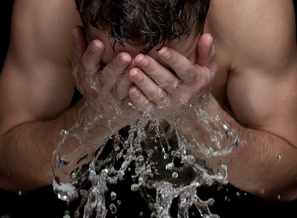man splashing hot water on his face