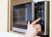 hand pressing button on microwave