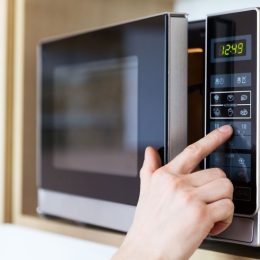 hand pressing button on microwave