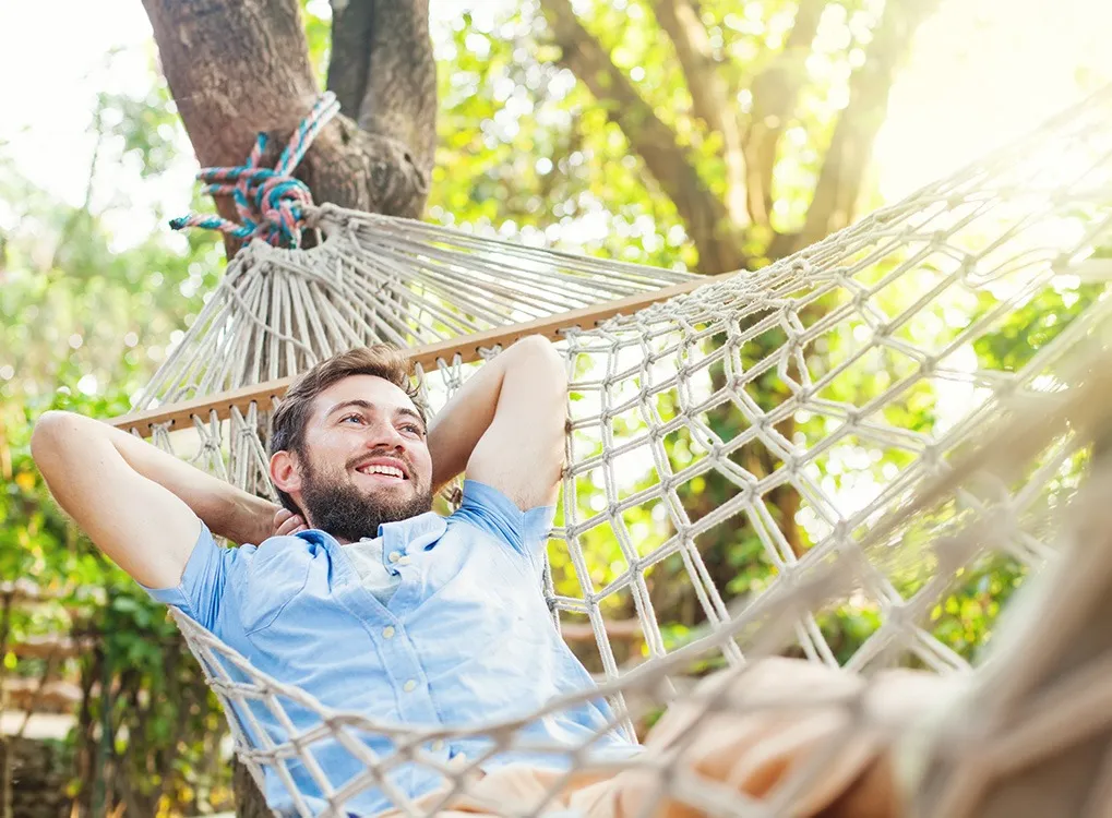 Young smiling man lounging in a hammock.
