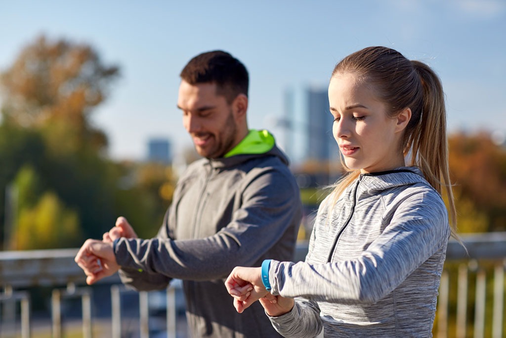 healthy man couple exercising checking smart watches fitbits