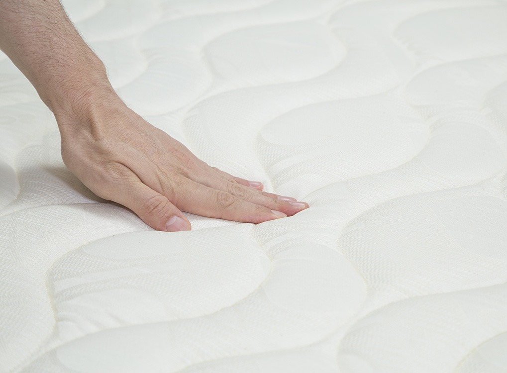 woman pressing down on mattress, signs you need a new mattress